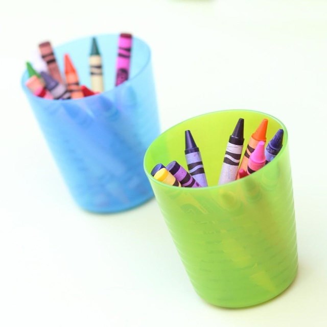 Zwei Plastikbecher mit bunten Buntstiften gefüllt, auf einem Tisch platziert.